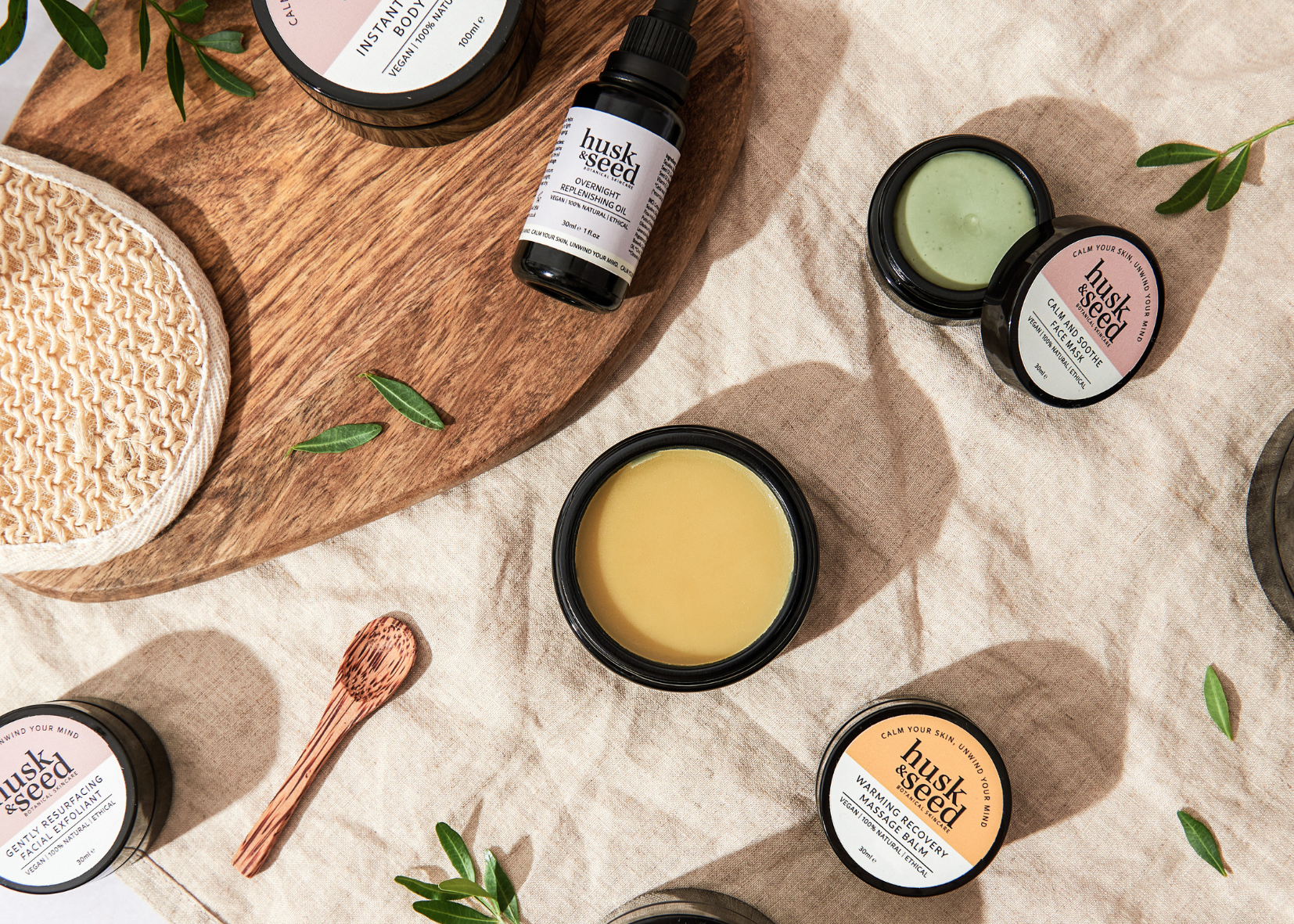 freshly hand-crafted botanical balms and oils with wooden spoon on natural cloth calm your skin unwind your mind