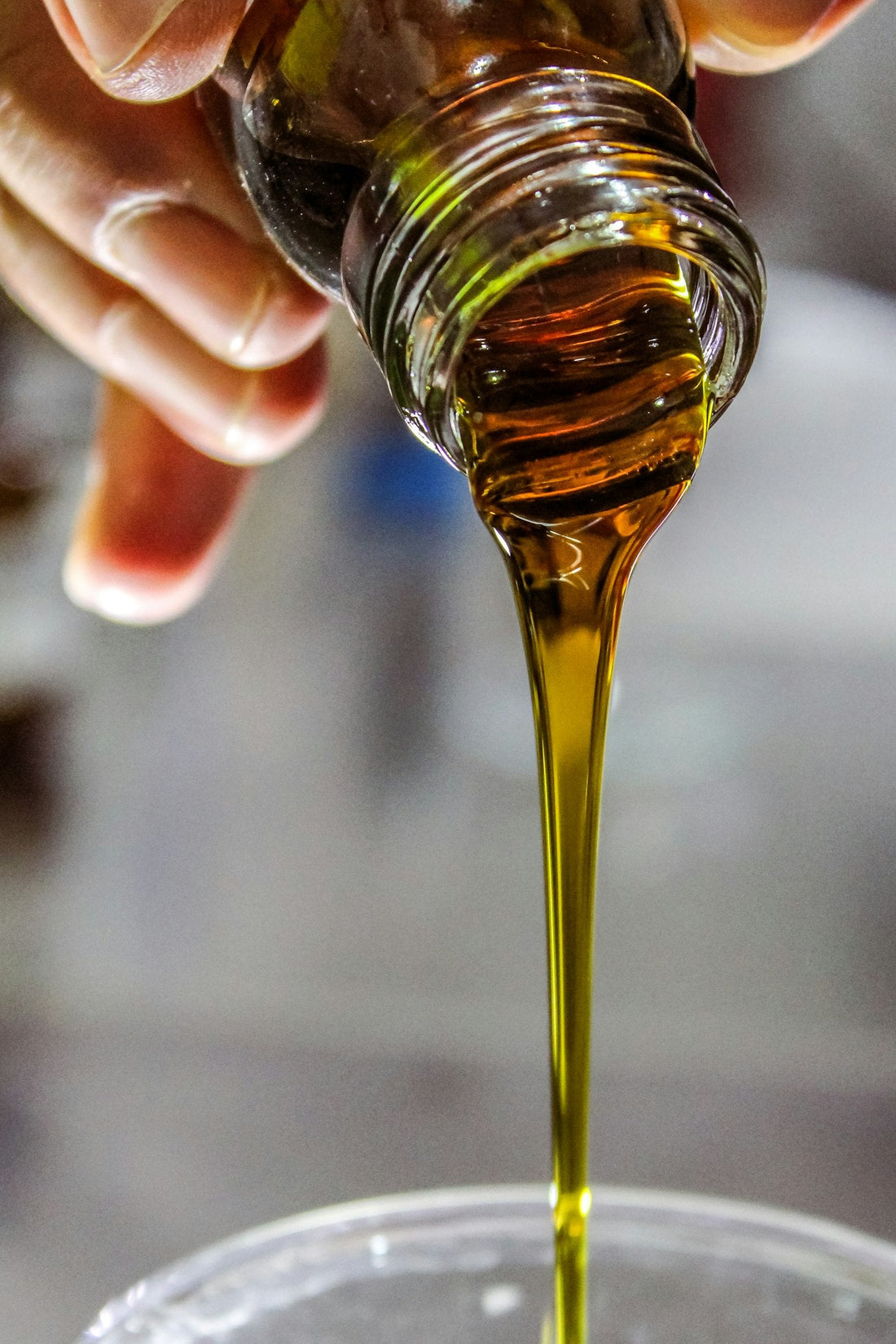 Golden botanical oil being poured from a glass bottle